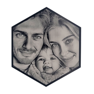 Hexagonal black-and-white portrait of a smiling family with two adults and a baby.